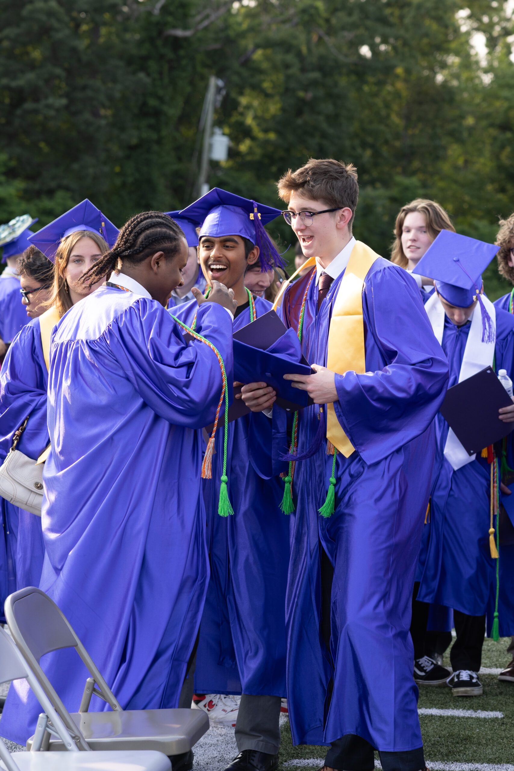 Graduates in purple robes hugging each other.