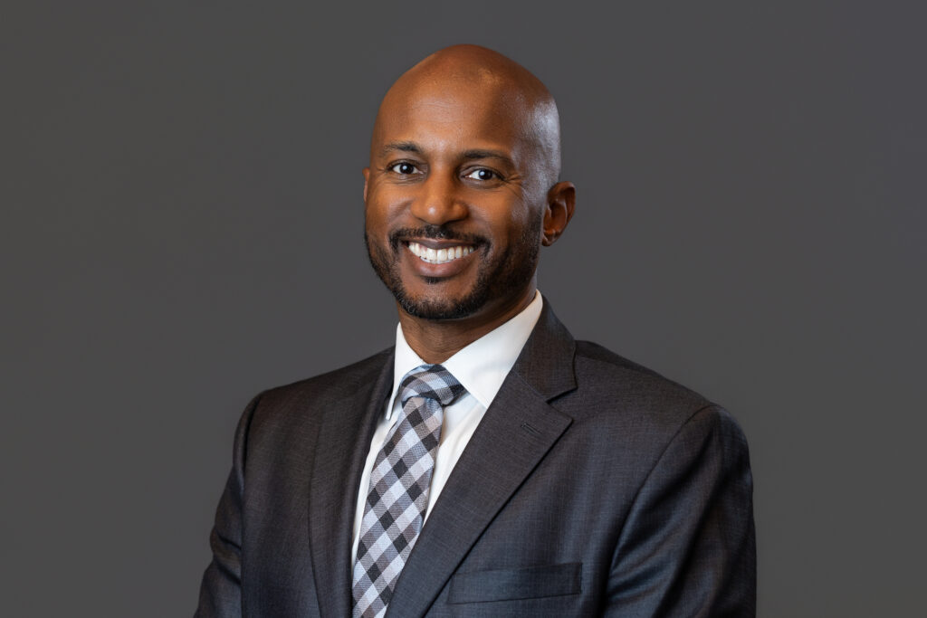 A man smiles at the camera in a professional headshot.