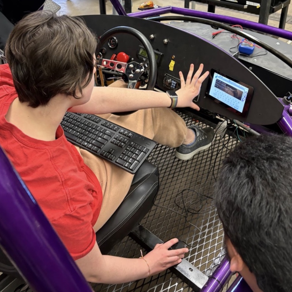 Student works on computer screen embedded in car dashboard.